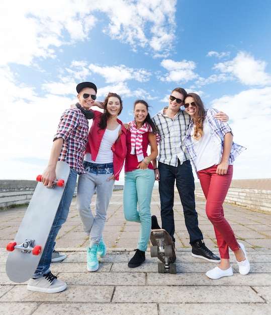 zomervakantie en tienerconcept - groep tieners met schaatsen buiten