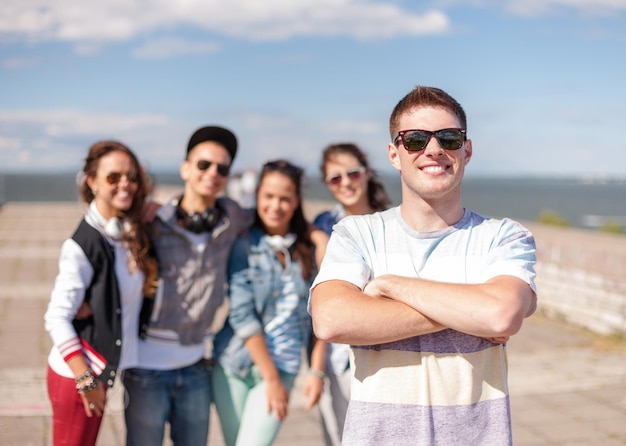 zomervakantie en tienerconcept - tiener in zonnebril die buiten met vrienden rondhangt