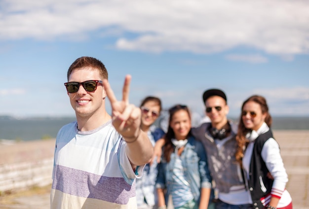 zomervakantie en tienerconcept - tiener in zonnebril die buiten met vrienden rondhangt