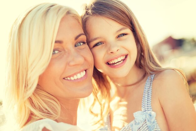 Foto zomervakantie, familie, kinderen en mensenconcept - gelukkig moeder en kindmeisje buitenshuis