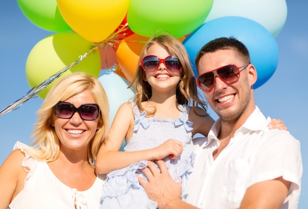 Foto zomervakantie, feest, kinderen en mensen concept - gelukkig gezin met kleurrijke ballonnen buitenshuis