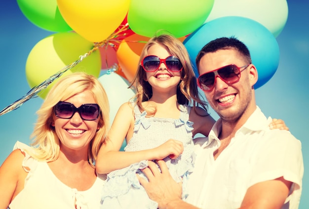 Foto zomervakantie, feest, kinderen en mensen concept - gelukkig gezin met kleurrijke ballonnen buitenshuis