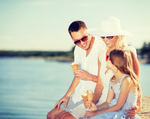 zomervakantie, feest, kinderen en mensen concept - gelukkige familie die ijs eet