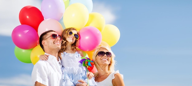 Foto zomervakantie, feest, kinderen en mensen concept - gezin met kleurrijke ballonnen
