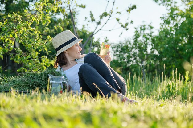 Zomervakantie in de tuin, vrouw tuinman zittend op vers gemaaid gras