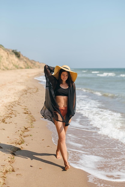 Zomervakantie mooie stijlvolle vrouw met hoed wandelen op zandstrand op zee golven en ontspannen