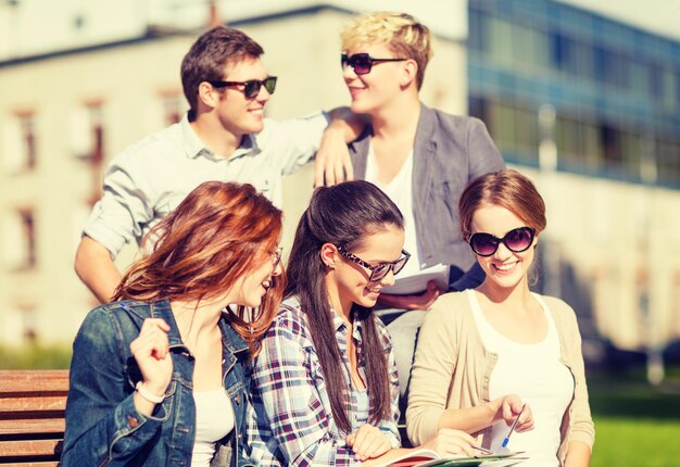 zomervakantie, onderwijs, campus en tienerconcept - groep studenten of tieners met boeken, notitieboekjes, bestanden en mappen