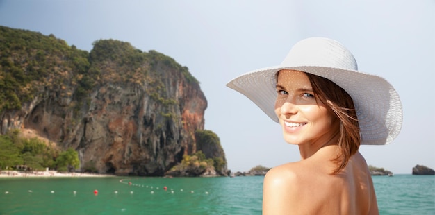 zomervakantie, reizen, mensen, toerisme en vakantie concept - gelukkige jonge vrouw in zonnehoed over bali strand met klif en zee achtergrond