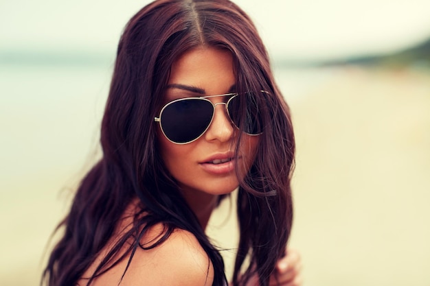 zomervakantie, toerisme, reizen, vakantie en mensenconcept - gezicht van jonge vrouw met zonnebril op strand