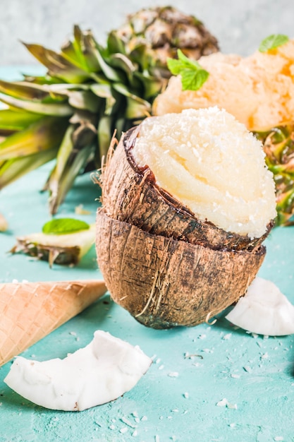 Foto zomervakantie vakantie concept, set verschillende tropische ijs sorbets, bevroren sappen in ananas, grapefruit en kokosnoot, lichtblauw beton