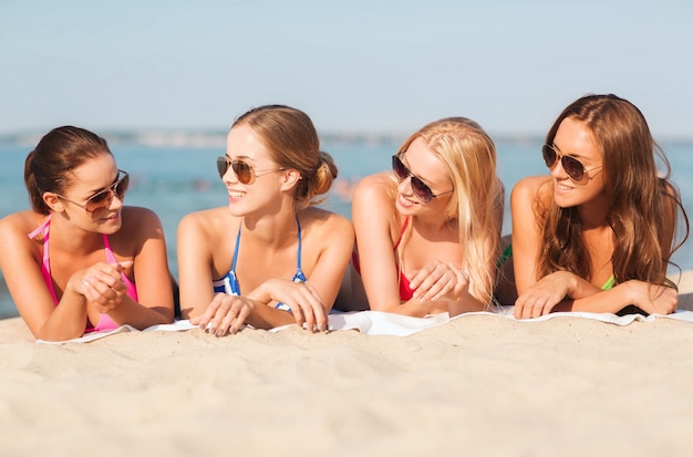 zomervakantie, vakantie, reizen en mensen concept - groep lachende jonge vrouwen in zonnebril liggend op het strand