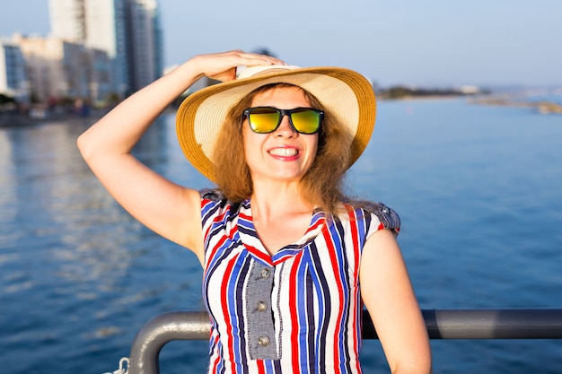 Zomervakantie, vakantie, reizen en mensen concept - lachende lachende jonge vrouw met zonnebril en hoed op het strand over zee.