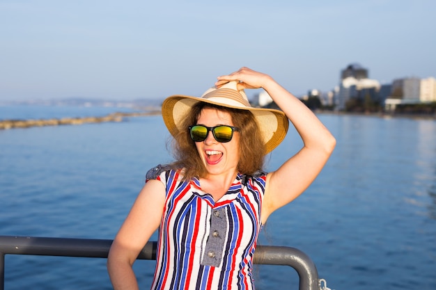 Zomervakantie, vakantie, reizen en mensen concept - lachende lachende jonge vrouw met zonnebril en hoed op het strand over zee.