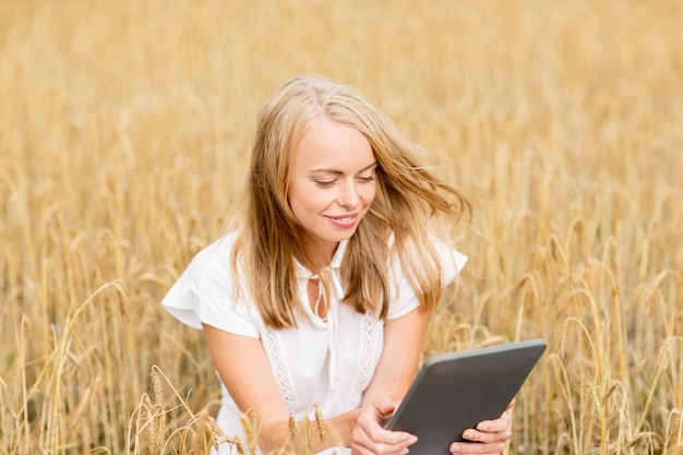 zomervakantie, vakantie, technologie en mensenconcept - glimlachende jonge vrouw in witte kleding met de computer van tabletpc op graangewassengebied