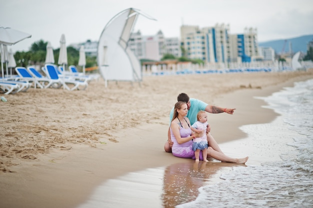 Zomervakanties. ouders en mensen buitenactiviteit met kinderen. fijne familievakanties. vader, zwangere moeder, dochtertje op zee zandstrand.