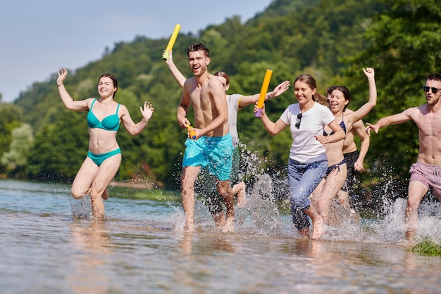 Zomervreugde groep gelukkige vrienden die plezier hebben tijdens het rennen en spetteren op de rivier