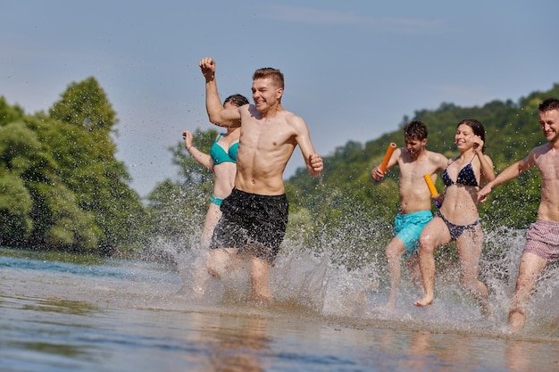 Zomervreugde groep gelukkige vrienden die plezier hebben tijdens het rennen en spetteren op de rivier