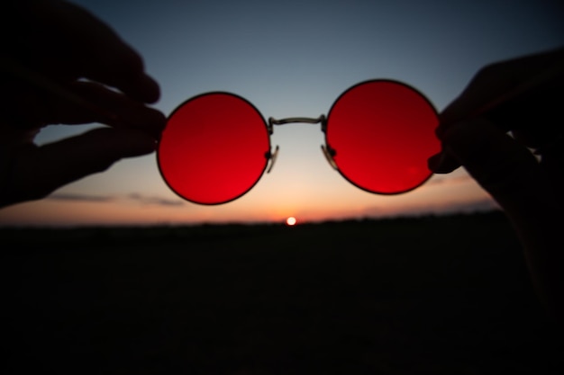 Zomerzonsondergang door de zonnebril met rode lenzen