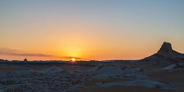 Zon en oranje lucht, silhouet van door de wind geërodeerde rotsformaties bij zonsondergang, Witte Woestijn. Egypte