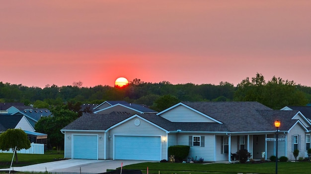 Zon ondergaat over het bos boom skyline voorstedelijke buurt huis oranje gloeiende lantaarnpaal