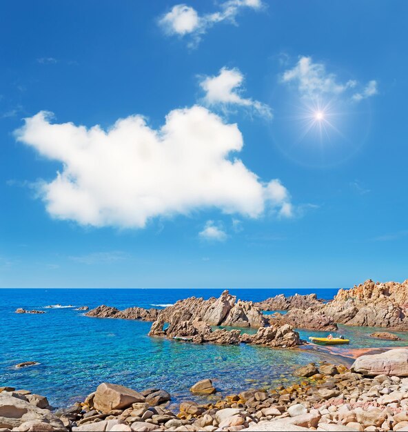 Zon schijnt in een blauwe lucht boven de rotskust van Costa Paradiso