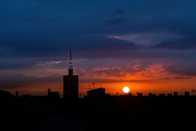 Zon stijgt boven de stad, dak bovenaanzicht van een oude kerktoren.