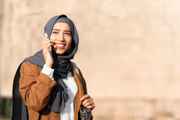 Zon verlicht een moslimvrouw die buiten met de mobiel praat