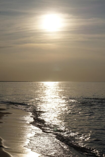 Zon weerkaatst in golven aan de kust bij zonsondergang