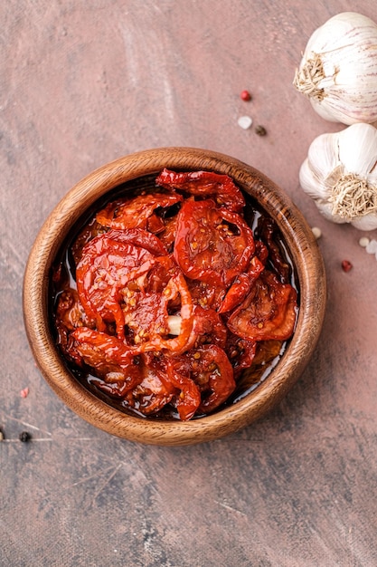 Zongedroogde tomaten in houten kom Gedroogde tomaten met olijfolie knoflook