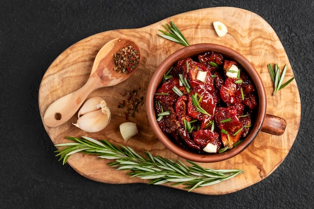 Foto zongedroogde tomaten met knoflook, rozemarijn en kruiden in een kom van klei