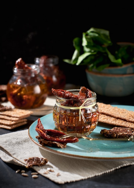 Zongedroogde tomaten met olijfolie in een pot roggebrood en een kapel