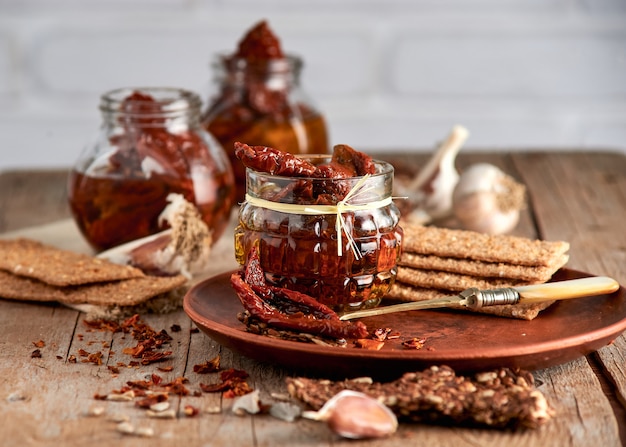 Zongedroogde tomaten met olijfolie in een pot roggebrood en een kapel