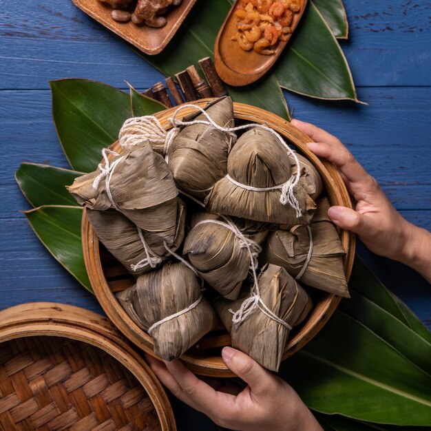 Концепция фестиваля лодок-драконов Zongzi Рисовые клецки традиционной китайской кухни на синем деревянном фоне для фестиваля Duanwu, вид сверху, концепция плоской планировки