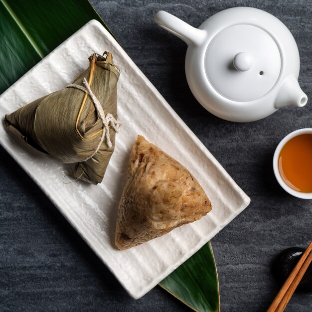 Zongzi. 어두운 검은 슬레이트 배경 위에 중국 전통 드래곤 보트 축제 (Duanwu 축제)에 대 한 쌀만 두 상위 뷰 디자인 개념.