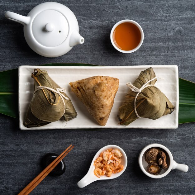 Zongzi. Rice dumpling top view design concept for Chinese traditional Dragon Boat Festival (Duanwu Festival) over dark black slate background.