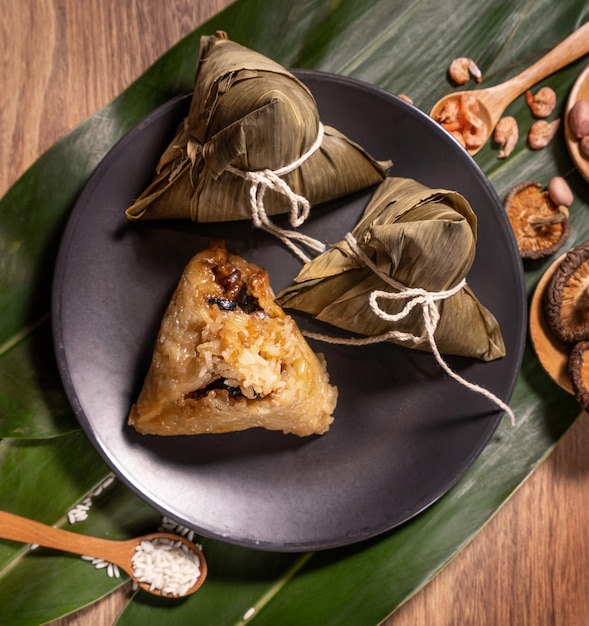 Zongzi steamed rice dumplings on wooden table bamboo leaves food in dragon boat festival duanwu concept close up copy space top view flat lay