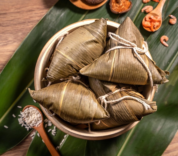 Zongzi 찐 쌀 만두 나무 테이블 대나무 잎 음식 드래곤 보트 축제 duanwu 개념 복사 공간 평면도 닫습니다