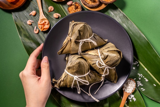 Zongzi, 녹색 테이블 배경에 찐 쌀 만두를 먹는 여자, 드래곤 보트 축제 duanwu 개념의 음식, 가까이, 복사 공간, 평면도, 평면 누워