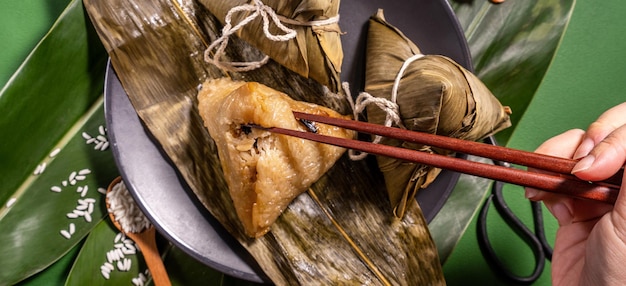 드래곤 보트 축제 duanwu 개념에서 녹색 테이블 배경 음식에 찐 쌀 만두를 먹는 Zongzi 여성은 복사 공간 평면도를 닫습니다