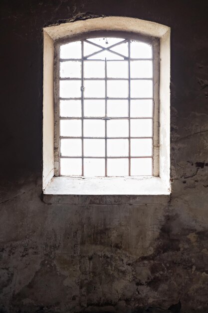 Zonlicht door oud raam aan de muur