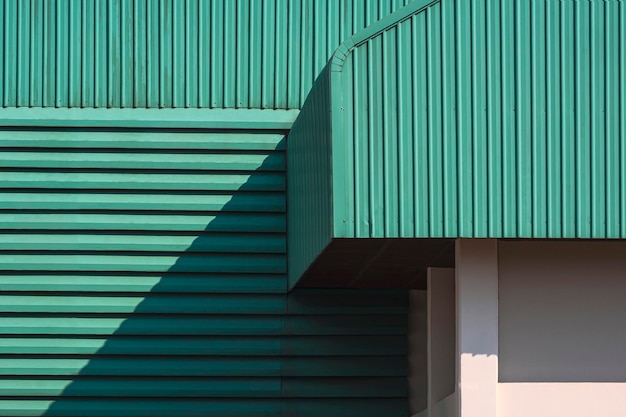 Zonlicht en schaduw op groen golfplaten dak met lamellen op de muur van fabrieksgebouw