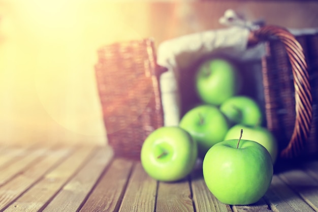 Zonlicht groene appel in een mand houten achtergrond