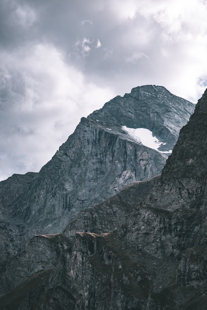 Zonlicht op alpiene vallei met gloeiende bergtoppen en schilderachtige wolken. Italiaanse Franse Alpen, bestemming zomerreizen, getinte afbeelding, vintage filter, gesplitste toon.