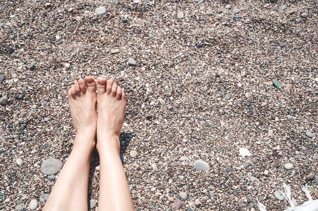 Zonnebaden en ontspannen meisje op het strand van de zee vrouwelijke voeten en benen op het strand onder de zon recre...