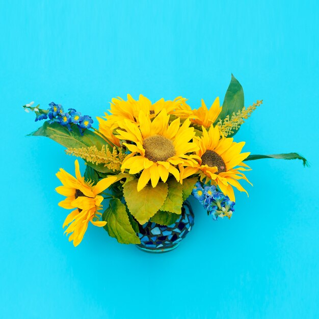 Zonnebloemen in een vaas op een blauwe achtergrond. Minimale kunst