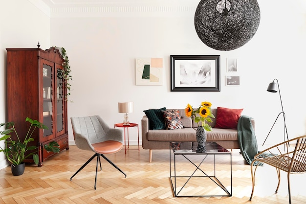 Zonnebloemen op tafel tussen fauteuils in wit plat interieur met posters boven bank Echte foto