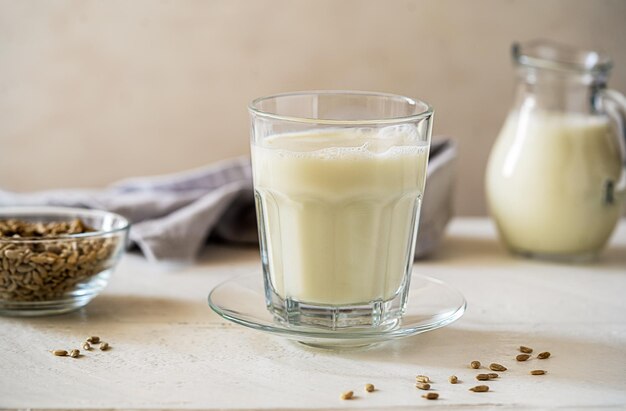 Zonnebloemmelk in glas met rauwe zaden melk pot servet op witte houten achtergrond
