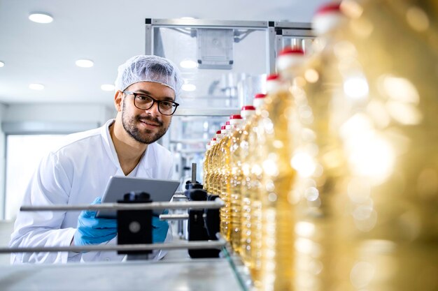 Zonnebloemolieproductie en arbeider die bij industriële machine staat en proces controleert;