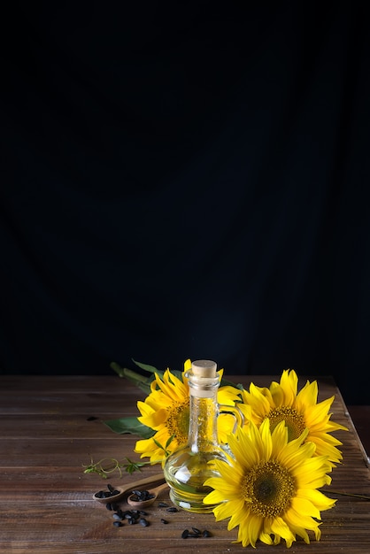 Zonnebloemzaden in een houten lepel en zonnebloemolie en mooie gele zonnebloemen