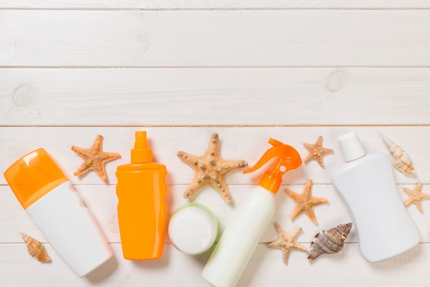 Zonnebrandcrème flessen met schelpen op witte houten tafel. Reizen gezondheidszorg accessoires bovenaanzicht.